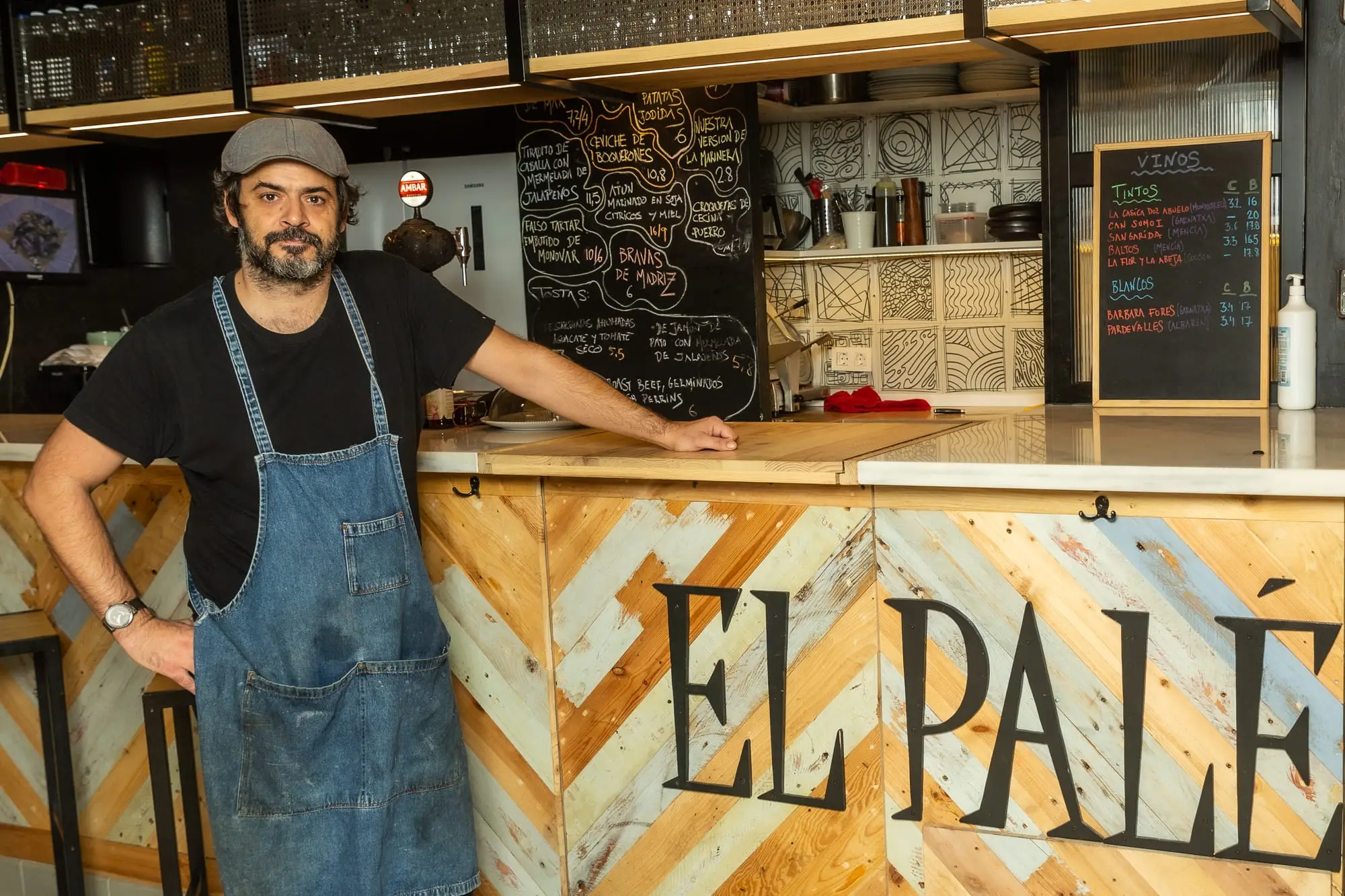 El frente de la barra de El Palé, de madera de palé con las letras EL PALÉ, y la pizarra con la carta detrás